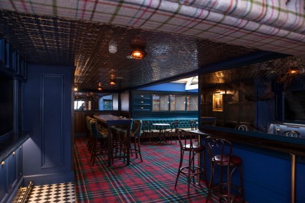 An empty pub/restaurant with dark furniture and a tarten floor
