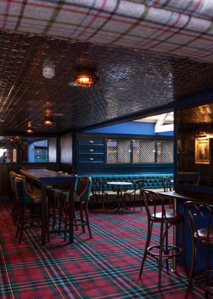 An empty pub/restaurant with dark furniture and a tarten floor